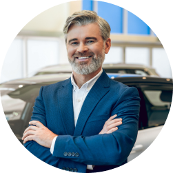Dealer principal standing with crossed arms inside dealership